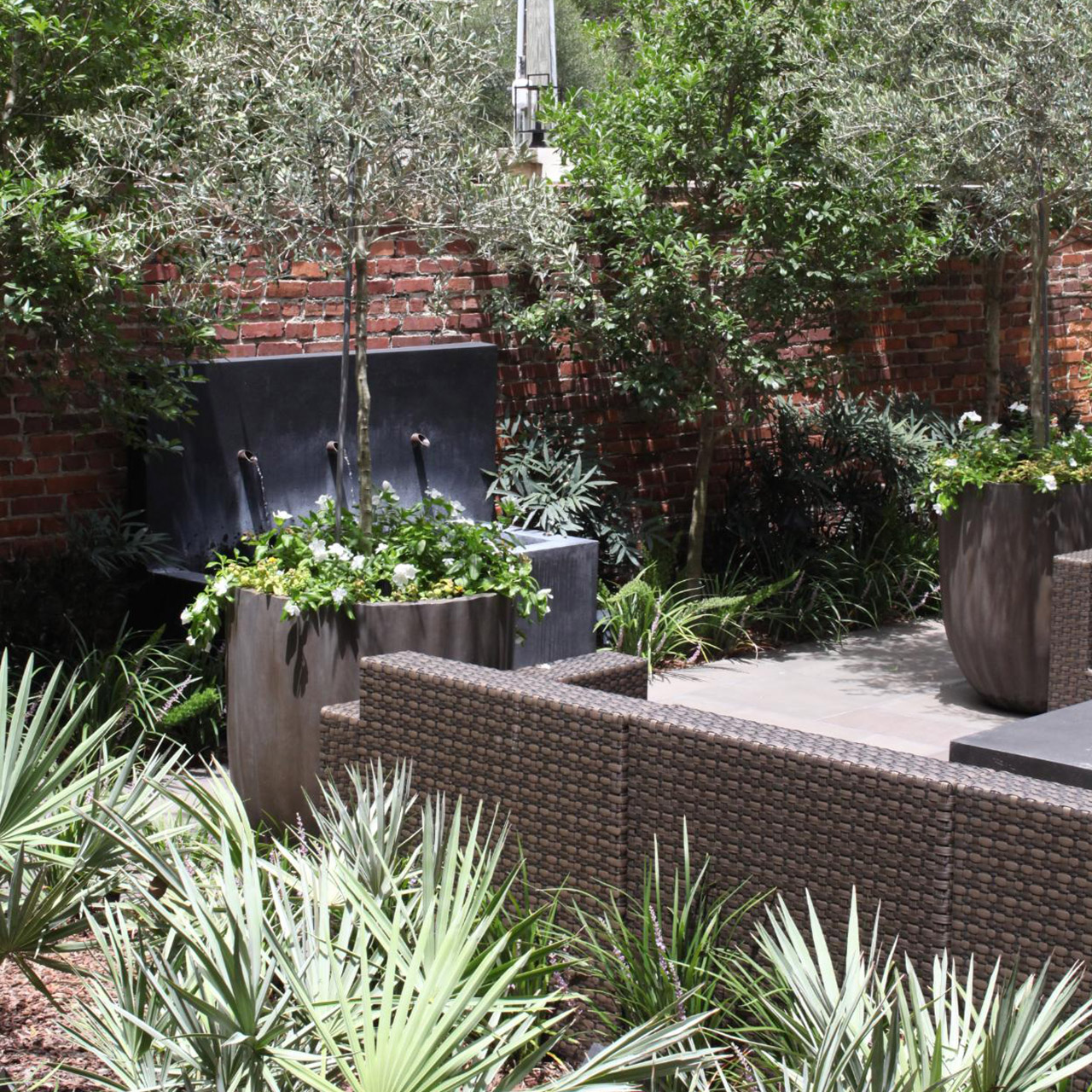 Modern courtyard with a brick wall in the background and a water feature.